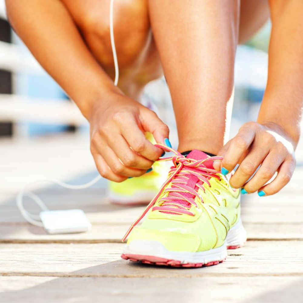 Person tying bright yellow and pink running shoes on a blurred background